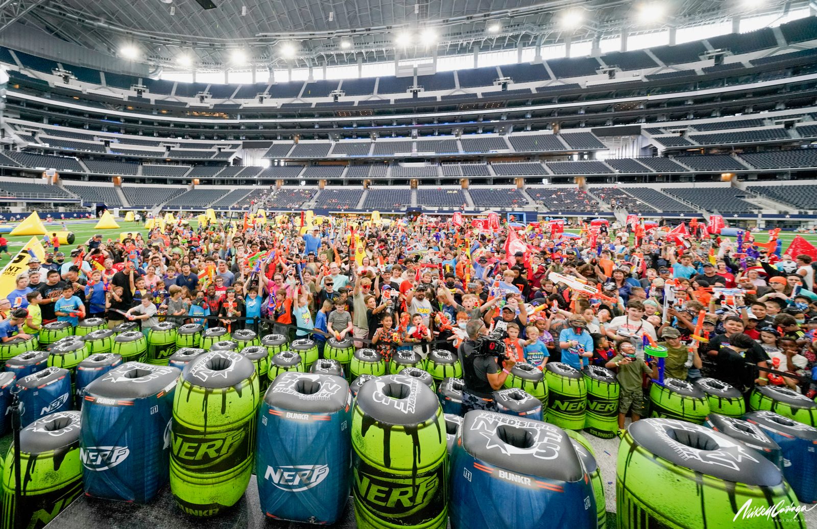 Players raising their foam blasters behind a row of inflatable Nerf bunkers at AT&T Stadium in June 2021