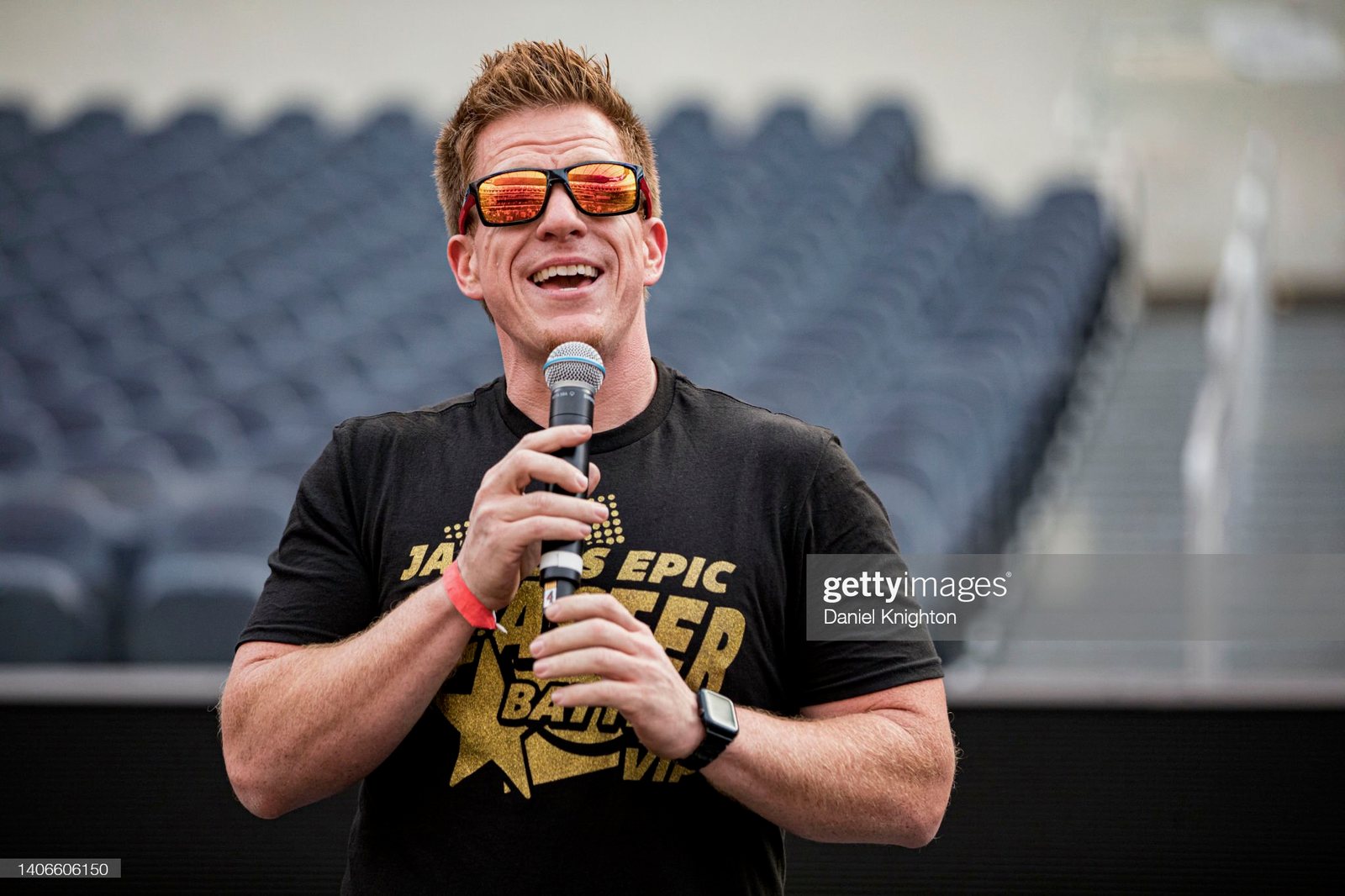 Jared Guynes laughing into a microphone in a Jared's Epic Blaster Battle VIP shirt