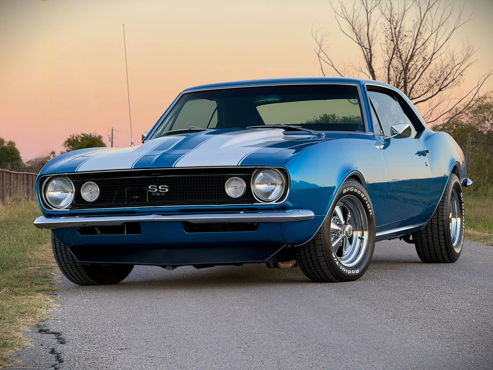 The restored blue 1967 Camaro SS with white stripes, parked at sunset
