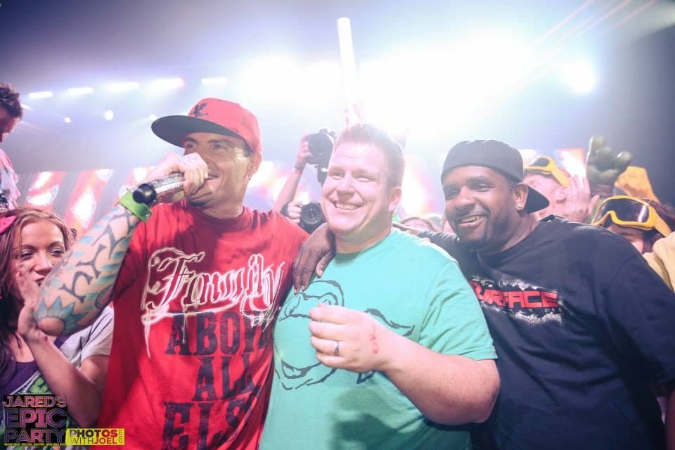 Jared Guynes on stage with two performers at the Epic Party