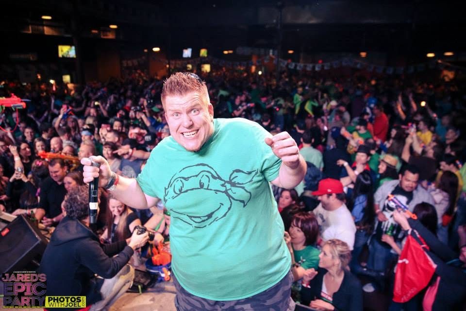 Jared Guynes in a Ninja Turtles shirt on stage in front of the Epic Party crowd