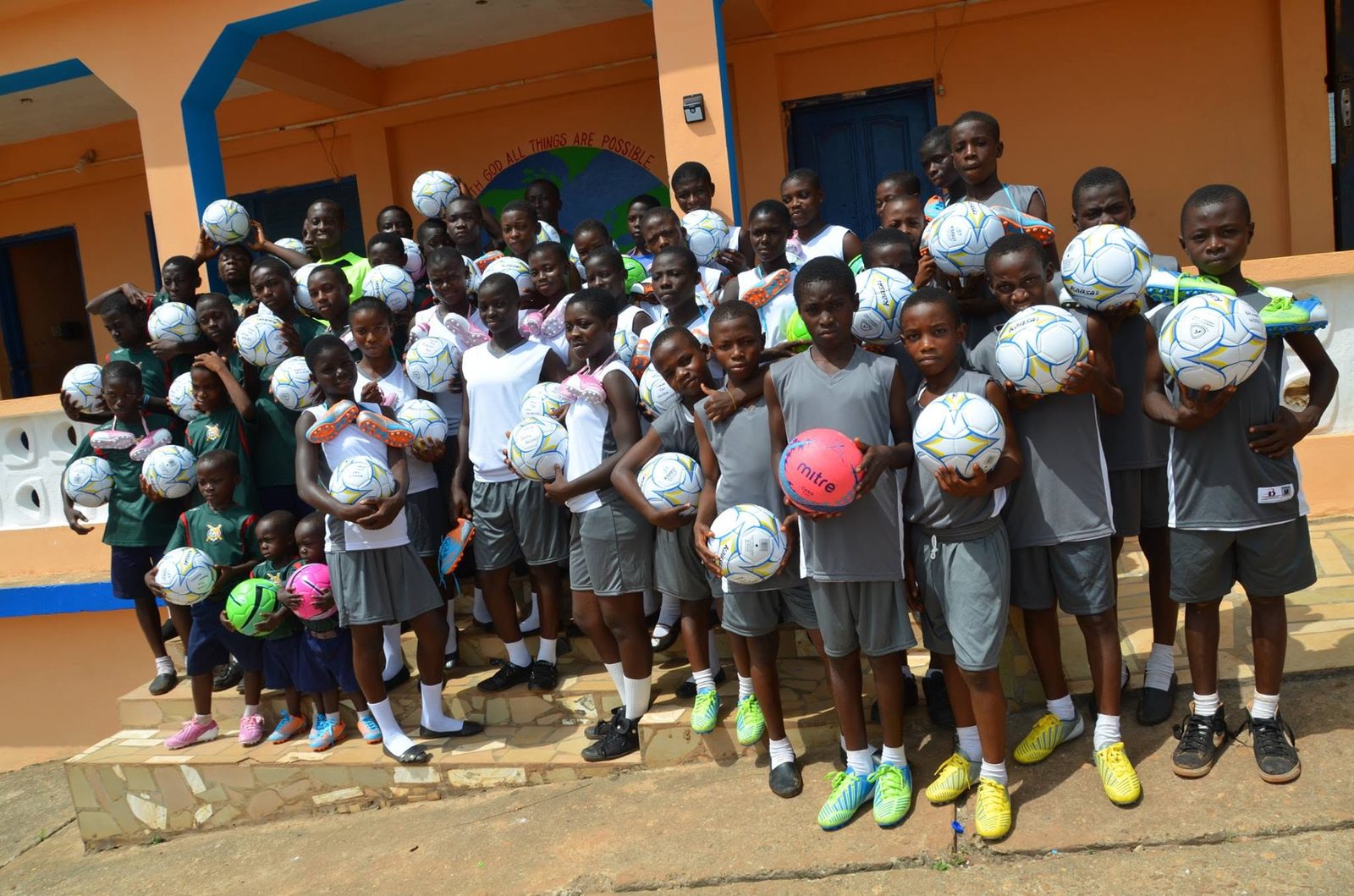 Schoolchildren in Ateiku, Ghana holding new soccer balls outside their school