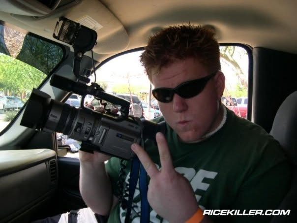 Jared Guynes in sunglasses holding a video camera inside a car
