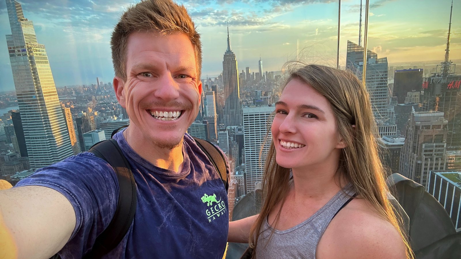 Jared Guynes and Jessica smiling high above Manhattan, with the Empire State Building behind them