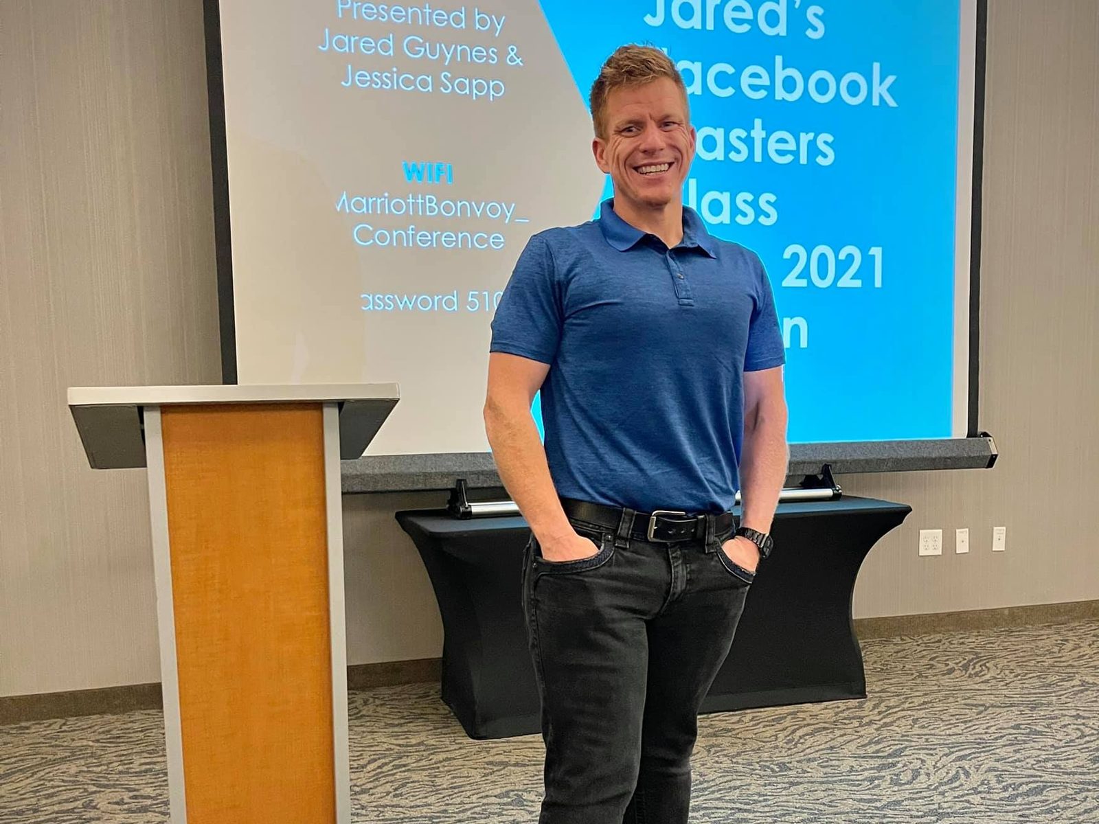Jared Guynes standing beside the podium in front of the title screen for Jared's Facebook Masters Class in 2021