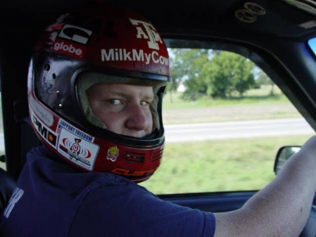 Jared Guynes behind the wheel in a racing helmet with a MilkMyCow sticker