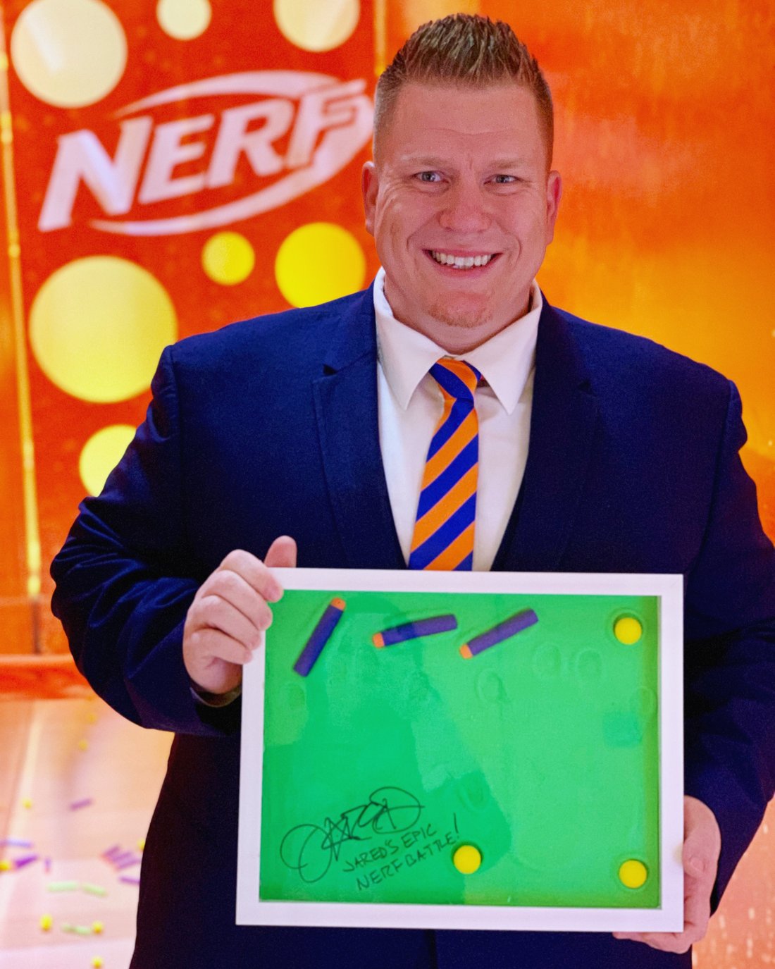 Jared Guynes holding his signed Play-Doh Wall of Fame plaque in front of a Nerf backdrop at New York Toy Fair