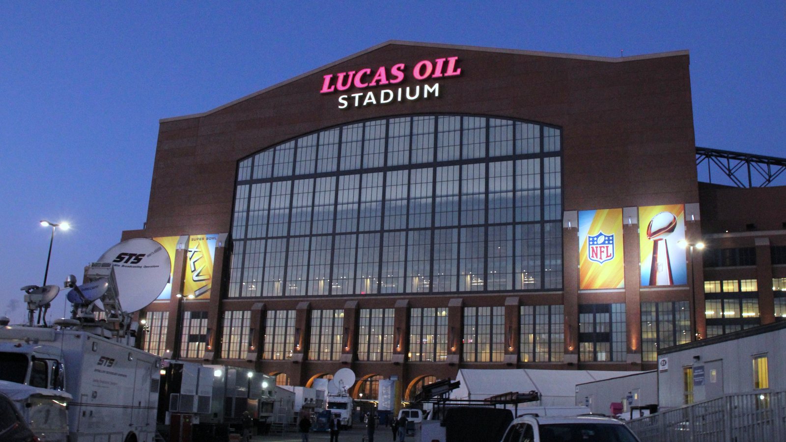 Lucas Oil Stadium in Indianapolis at dusk, with its red sign lit against a deep blue sky