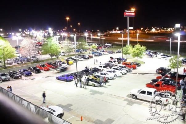 Hundreds of cars parked under the lights at a nighttime RiceKiller.com car meet