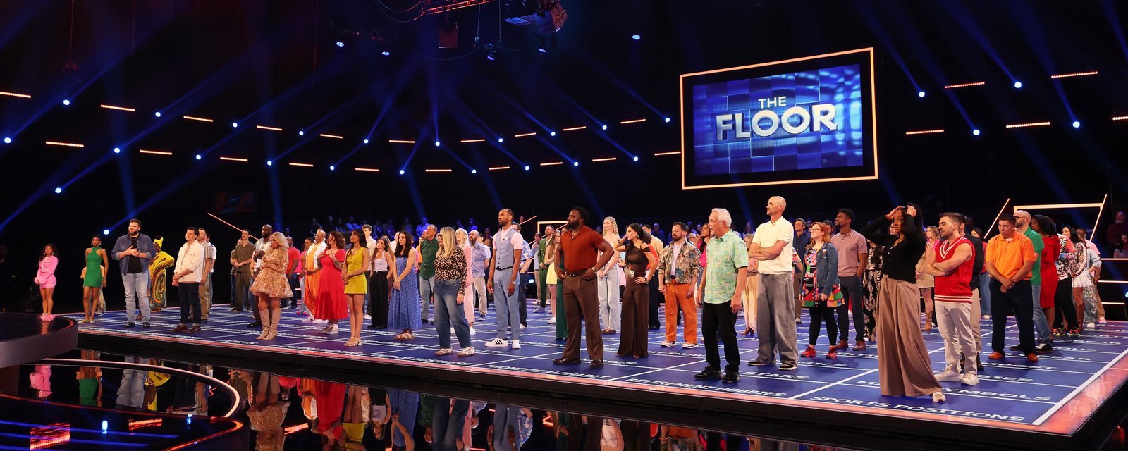 The Season 6 cast of The Floor standing on the lit board beneath the show's screen